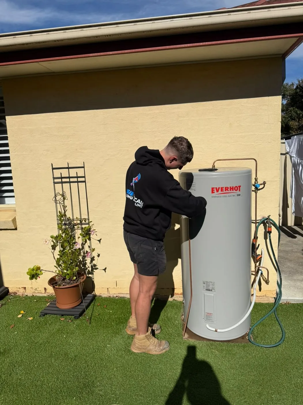 Electric storage hot water unit being installed outside a home