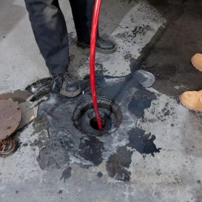 High-pressure water jetting hose feeding into a blocked drain