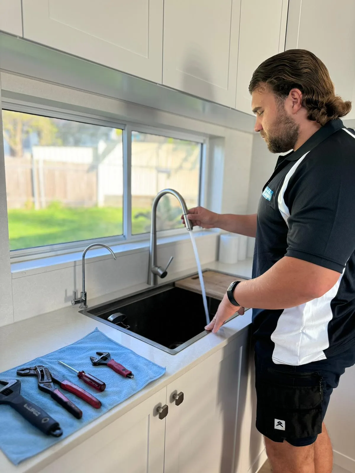Plumber checking flow at a kitchen sink