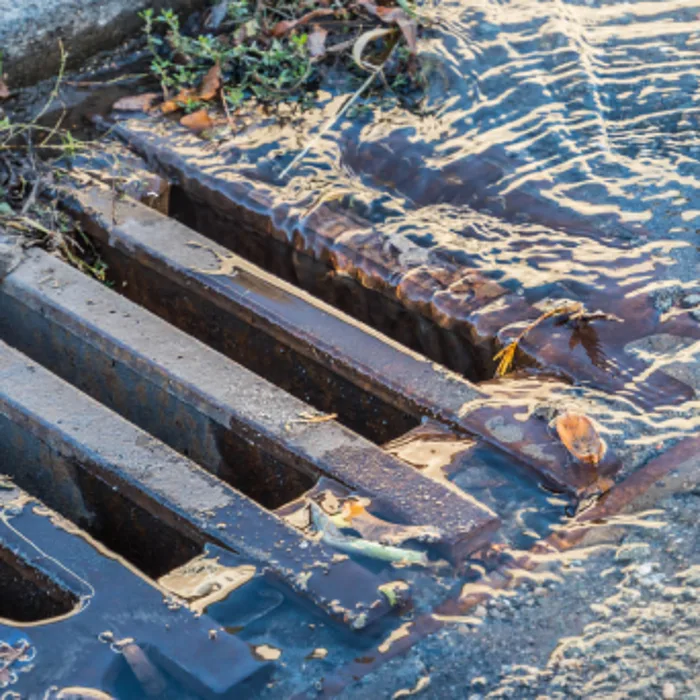 A blocked stormwater grate backing up after rain