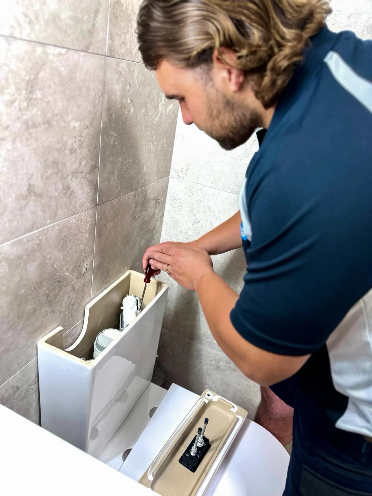Plumber servicing a concealed toilet cistern